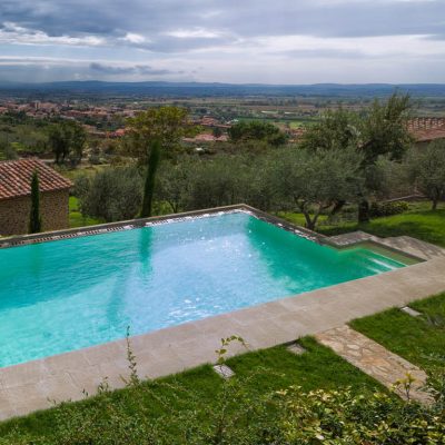 piscina a sfioro su terreno terrazzato color sabbia